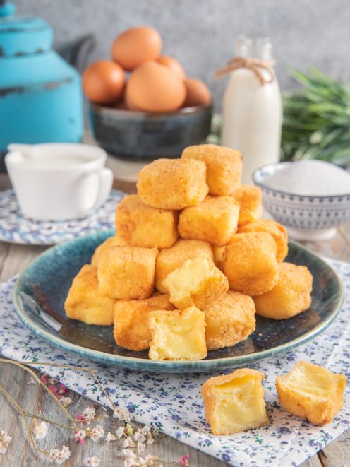 Crema fritta impilata a piramide, con uno spezzato che mostra il cuore morbido di crema pasticcera