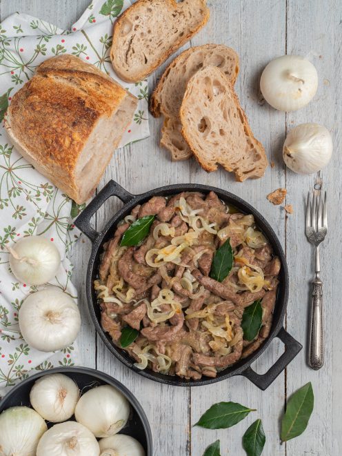 Fegato alla veneziana in padella di ferro con cipolle stufate e foglie di alloro, servito con pane rustico