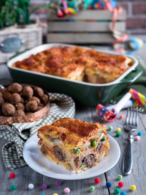 Lasagne di Carnevale con strati di ragù, piselli e besciamella, gratinate e servite a fetta