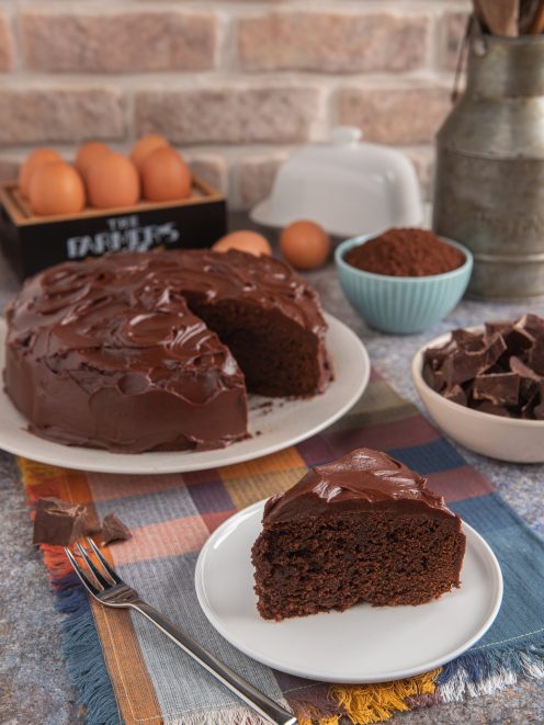 Mud cake al cioccolato con glassa lucida, fetta servita accanto alla torta tagliata