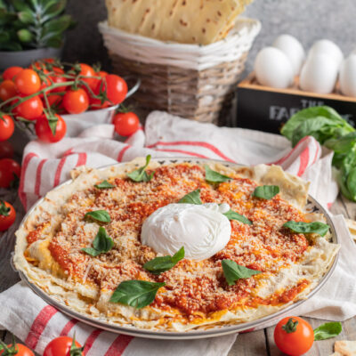 Pane frattau con salsa di pomodoro, parmigiano grattugiato, burrata al centro e foglie di basilico
