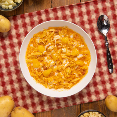 Pasta patate e provola in brodo di pomodoro con pezzi di patata e filamenti di formaggio fuso