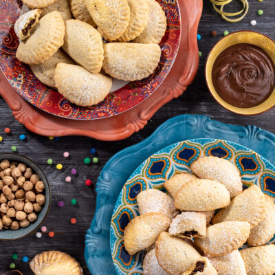 Ravioli dolci di carnevale ripieni di cioccolato e spolverati di zucchero a velo su due piatti