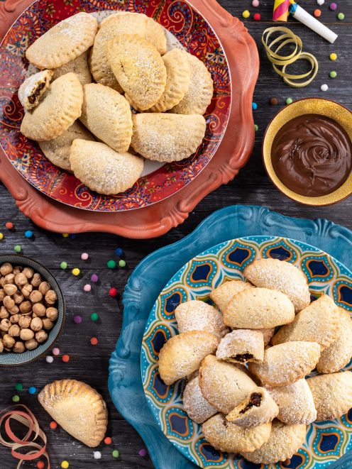 Ravioli dolci di carnevale ripieni di cioccolato e spolverati di zucchero a velo su due piatti