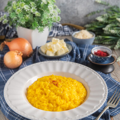 Risotto allo zafferano cremoso e dorato, guarnito con pistilli di zafferano