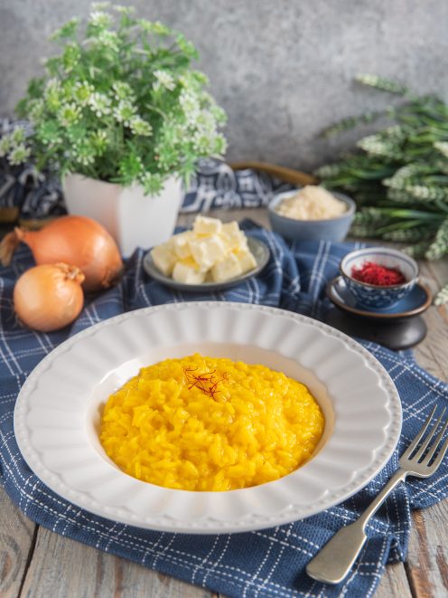 Risotto allo zafferano cremoso e dorato, guarnito con pistilli di zafferano