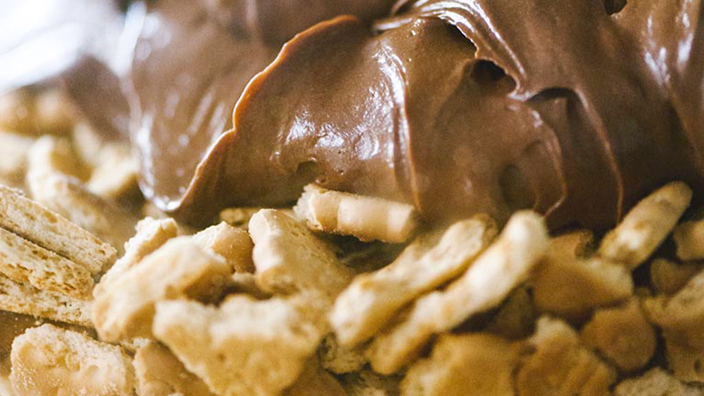 Biscotti sbriciolati immersi nella crema al cioccolato per il salame di cioccolato