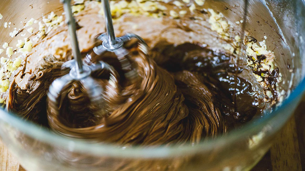 Impasto al cioccolato fuso lavorato con le fruste elettriche insieme a granella di nocciole