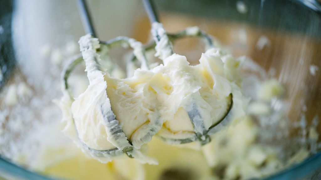 Burro montato a crema con le fruste elettriche, soffice e spumoso