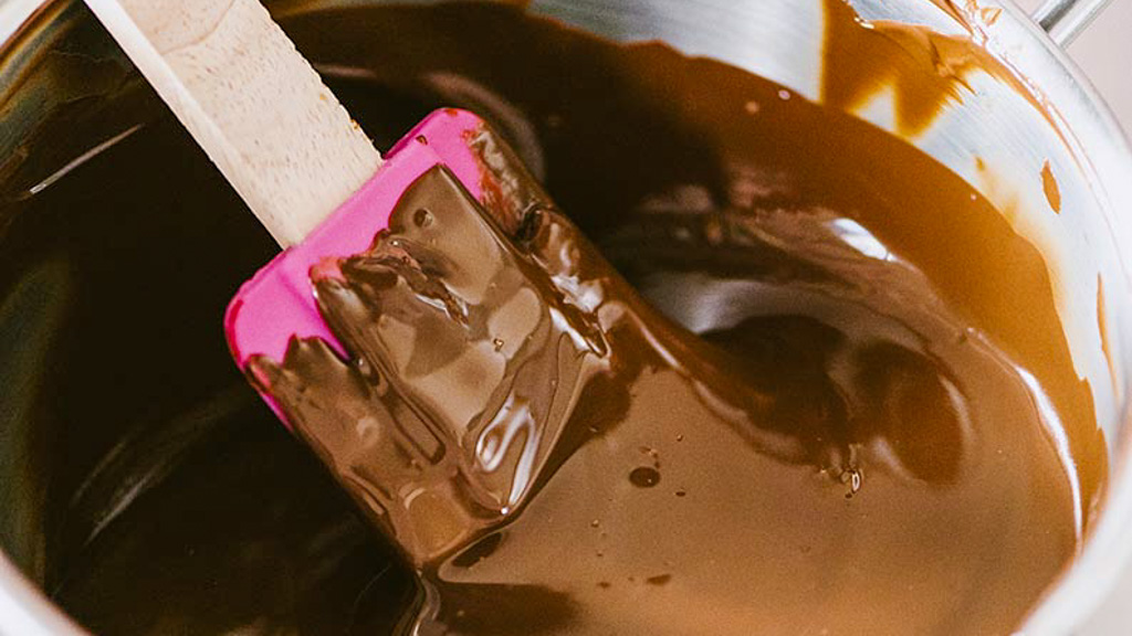 Cioccolato fuso e lucido mescolato con una spatola in una ciotola