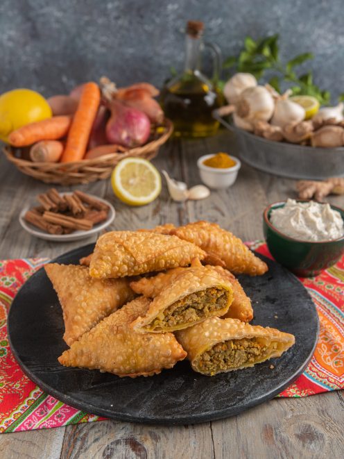 Samosa fritti con pasta croccante e ripieno di carne speziata, uno tagliato a metà