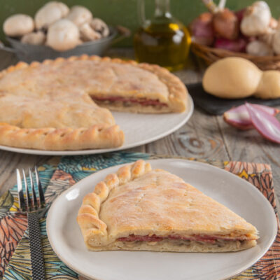 Schiacciata ai funghi e salame con provola, una fetta in primo piano che mostra il ripieno