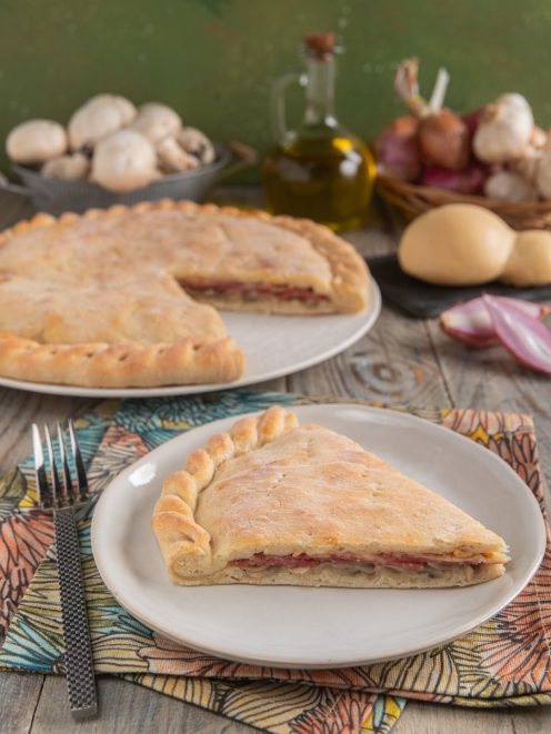 Schiacciata ai funghi e salame con provola, una fetta in primo piano che mostra il ripieno