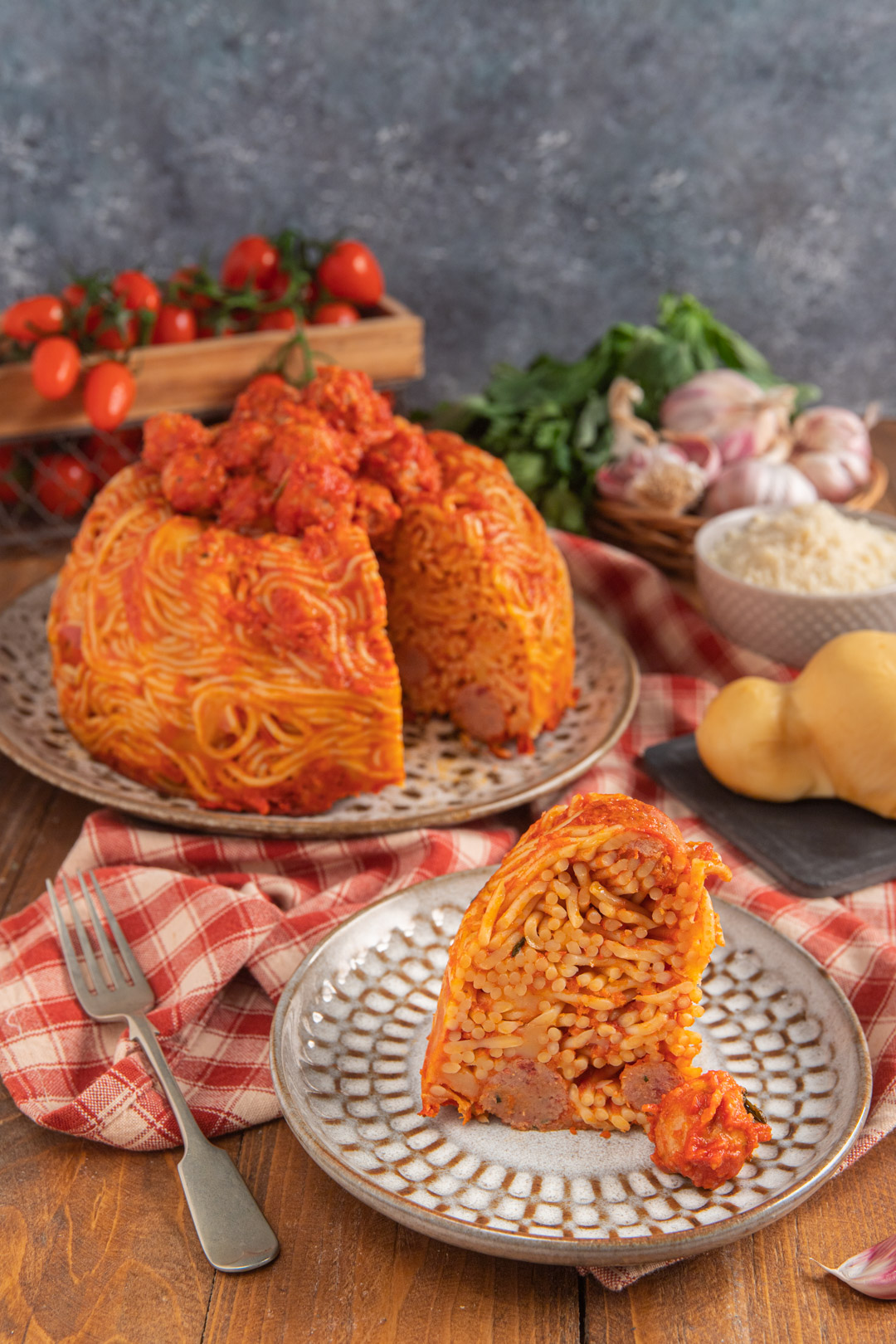 Timballo di pasta con polpette di cotechino al sugo, servito intero e con una fetta già tagliata che ne mostra il ripieno