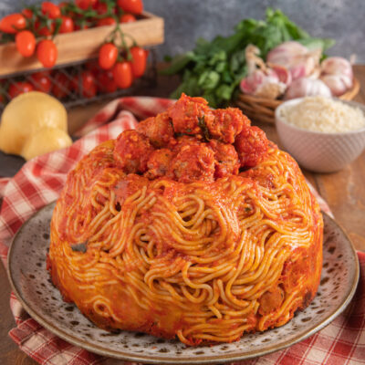 Timballo di pasta con polpette di cotechino al sugo, sformato a cupola e guarnito con ragù in superficie