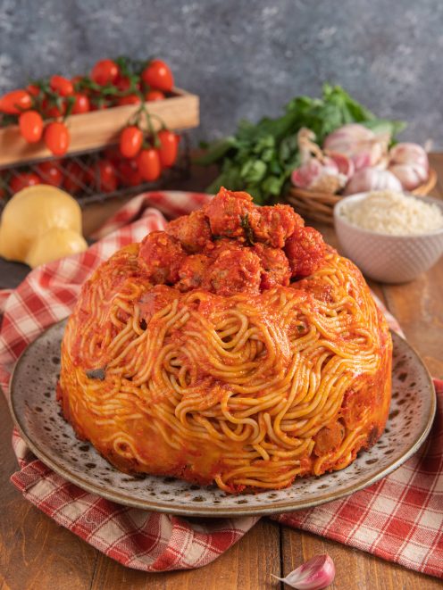 Timballo di pasta con polpette di cotechino al sugo, sformato a cupola e guarnito con ragù in superficie