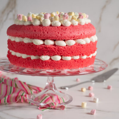 Torta di compleanno rosa a strati farciti con crema al burro e marshmallow colorati sulla sommità
