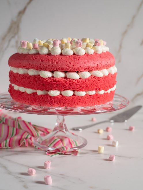 Torta di compleanno rosa a strati farciti con crema al burro e marshmallow colorati sulla sommità