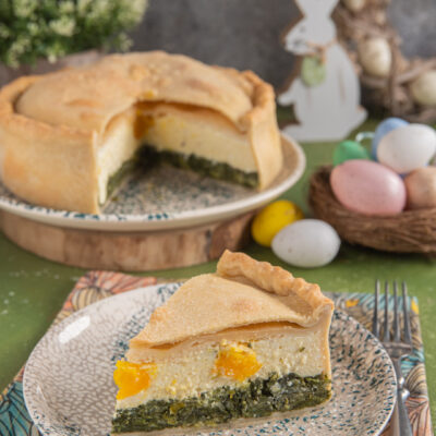 Torta pasqualina in sezione con strati di erbette, ricotta e uova sode intere