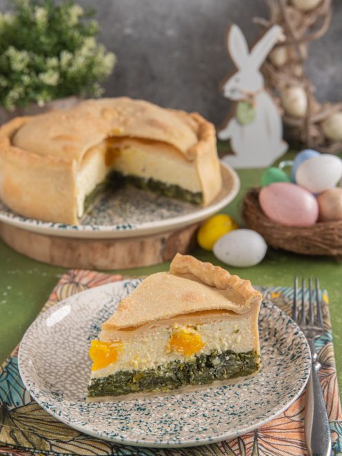 Torta pasqualina in sezione con strati di erbette, ricotta e uova sode intere