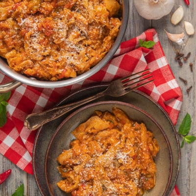 Trippa alla romana con sugo di pomodoro ricco, servita in ciotola e nella pentola, spolverata di pecorino grattugiato