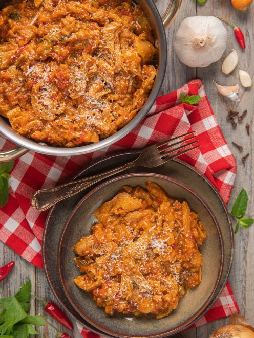 Trippa alla romana con sugo di pomodoro ricco, servita in ciotola e nella pentola, spolverata di pecorino grattugiato