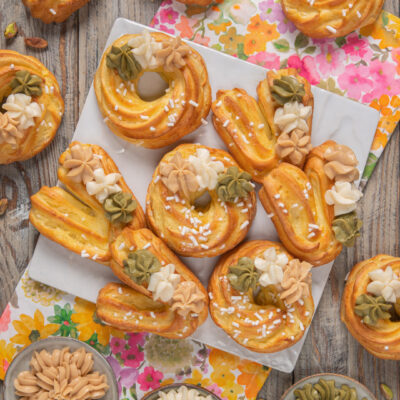 Foto via col vento con eclair e ciambelle di pasta choux decorate con ciuffi di crema al pistacchio, caffe e vaniglia