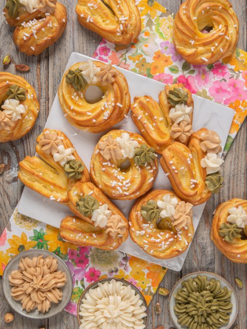 Foto via col vento con eclair e ciambelle di pasta choux decorate con ciuffi di crema al pistacchio, caffe e vaniglia