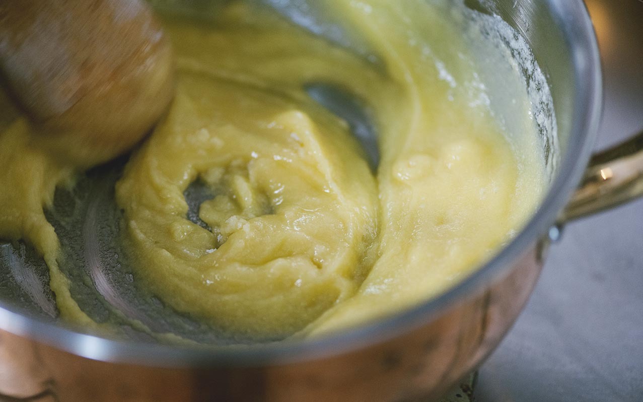 Composto giallo denso mescolato con un cucchiaio di legno in un pentolino