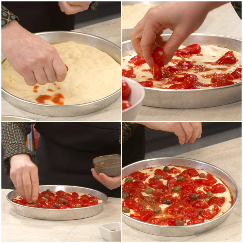 Pomodorini schiacciati sulla focaccia barese con olive e origano sparsi sull'impasto