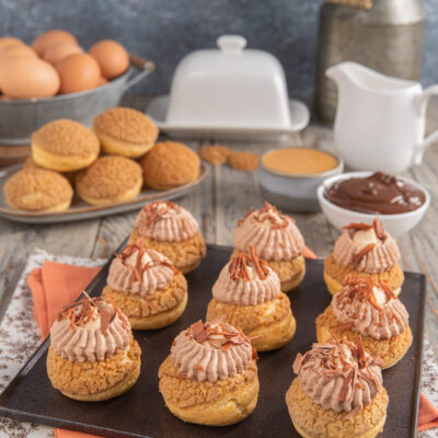 Bignè craquelin farciti con crema al cioccolato e arachidi, guarniti con scaglie di cioccolato