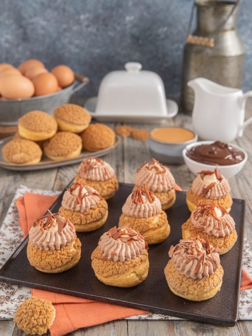 Bignè craquelin farciti con crema al cioccolato e arachidi, guarniti con scaglie di cioccolato