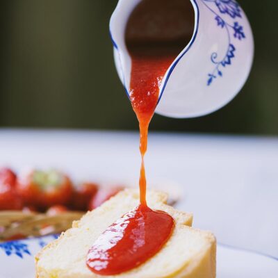 Coulis di fragole versato su una fetta di rotolo soffice alla crema
