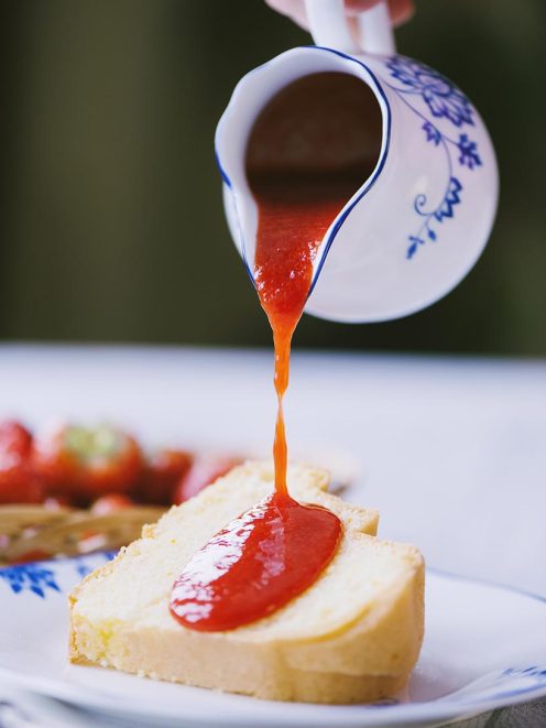 Coulis di fragole versato su una fetta di rotolo soffice alla crema