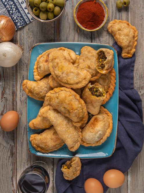 Empanadas argentine di carne fritte, alcune aperte con ripieno di carne macinata e uova sode