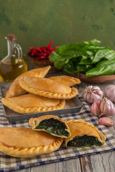 Falagoni lucani ripieni di verdure a foglia verde, uno aperto a mostrare il cuore filante