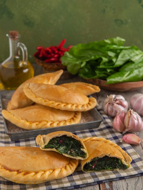 Falagoni lucani ripieni di verdure a foglia verde, uno aperto a mostrare il cuore filante
