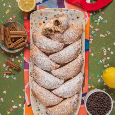 Fravioli siciliani a mezzaluna fritti, spolverati di zucchero a velo e farciti di ricotta e cioccolato