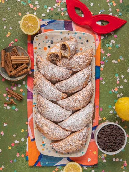Fravioli siciliani a mezzaluna fritti, spolverati di zucchero a velo e farciti di ricotta e cioccolato