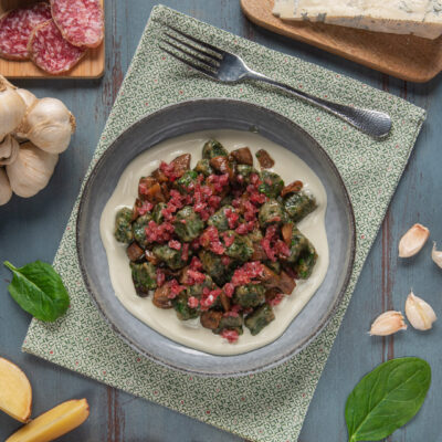 Gnocchetti agli spinaci con salame e funghi su crema di gorgonzola, circondati da patate e aglio