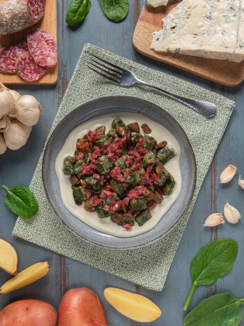 Gnocchetti agli spinaci con salame e funghi su crema di gorgonzola, circondati da patate e aglio