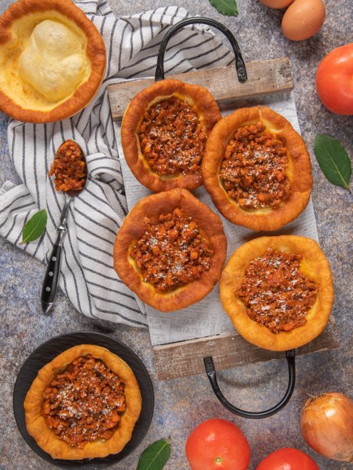 Kniekiechl salati farciti con ragù di carne e spolverata di parmigiano su tagliere di legno