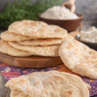 Pane naan appena cotto, uno spezzato in primo piano che mostra la mollica soffice all'interno