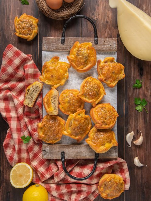 Pastieri ragusani dorati al forno con ripieno di carne, uno tagliato a metà per mostrare l'interno
