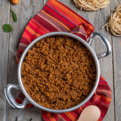 Ragù alla bolognese ricco e denso, con nidi di pasta fresca e carote sullo sfondo