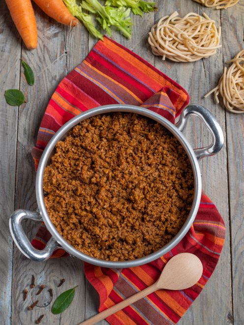 Ragù alla bolognese ricco e denso, con nidi di pasta fresca e carote sullo sfondo