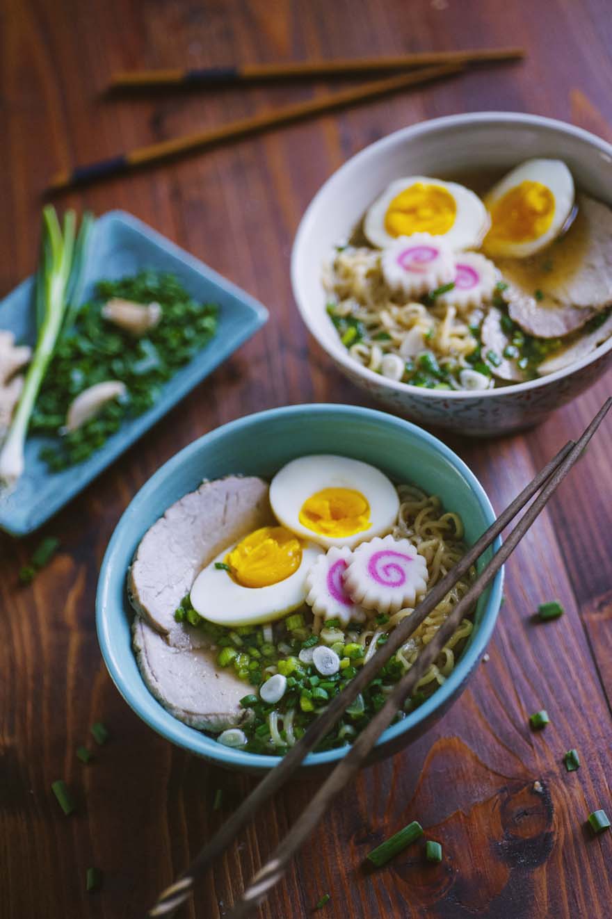 Ramen con noodles, uova sode tagliate a metà, chashu di maiale e narutomaki su brodo con erba cipollina