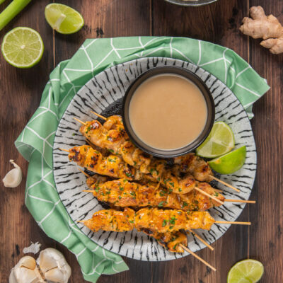 Satay di pollo grigliato su spiedini con salsa di arachidi e spicchi di lime