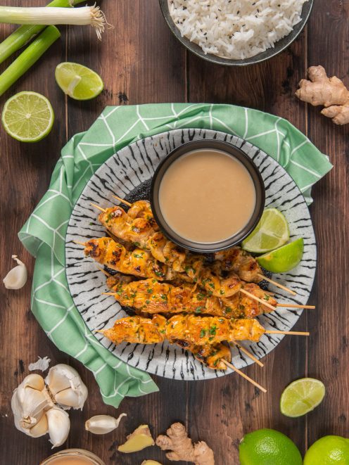 Satay di pollo grigliato su spiedini con salsa di arachidi e spicchi di lime