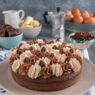 Torta al cioccolato e caffè decorata con ciuffi di crema alternati e chicchi di caffè al cioccolato